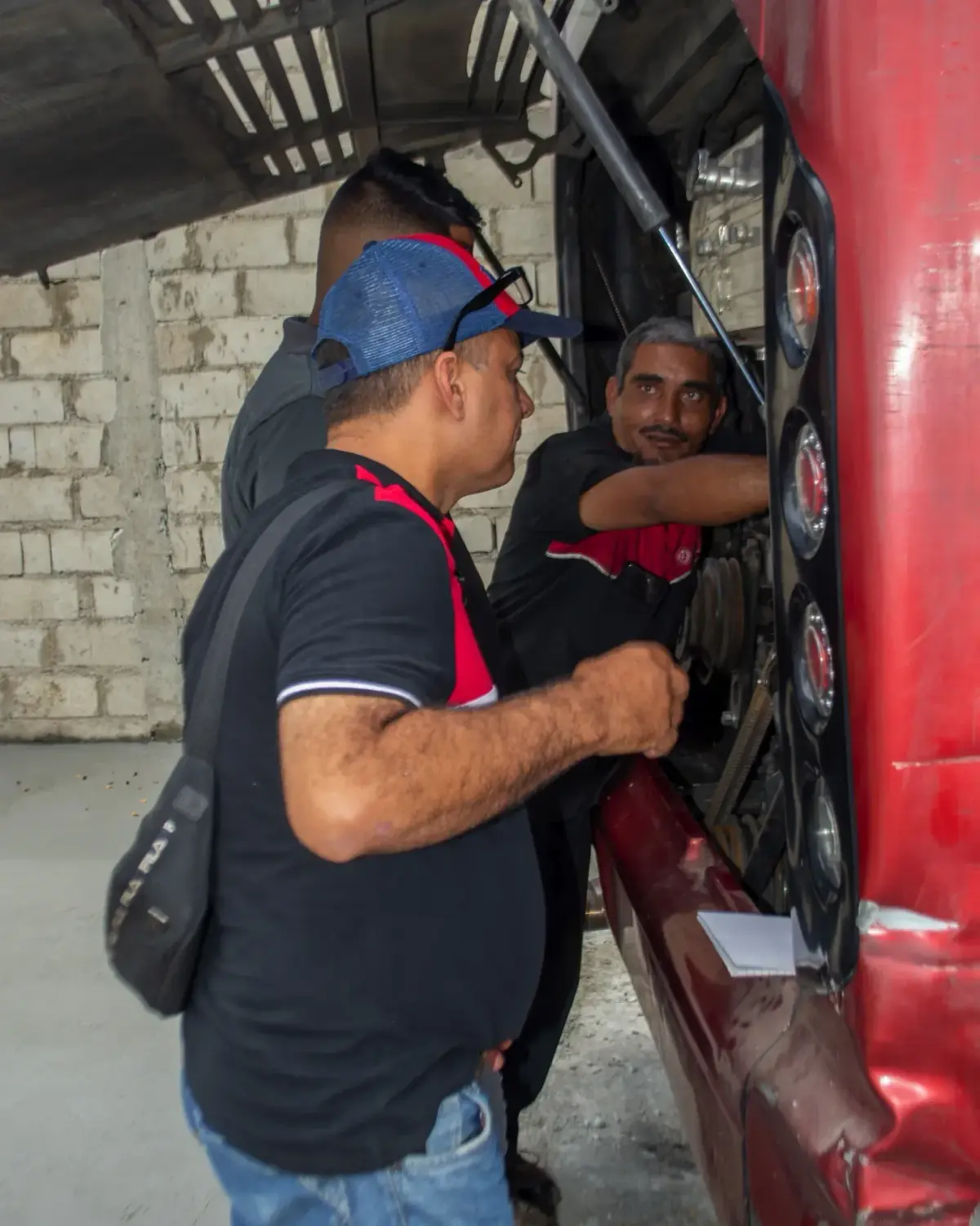 Participantes trabajando sobre el motor de un camión con el capó abierto