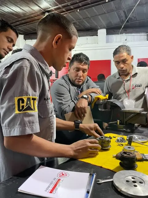 Participantes examinando componentes de turbo dispuestos sobre el banco
