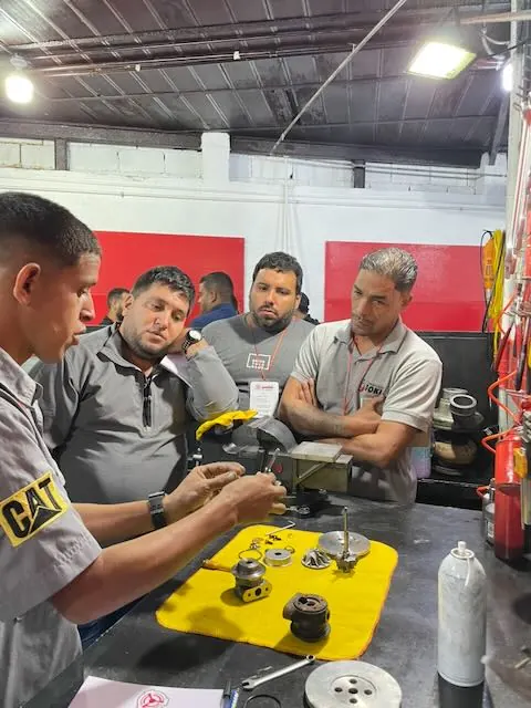 Instructor mostrando las piezas de un turbo desarmadas sobre el banco