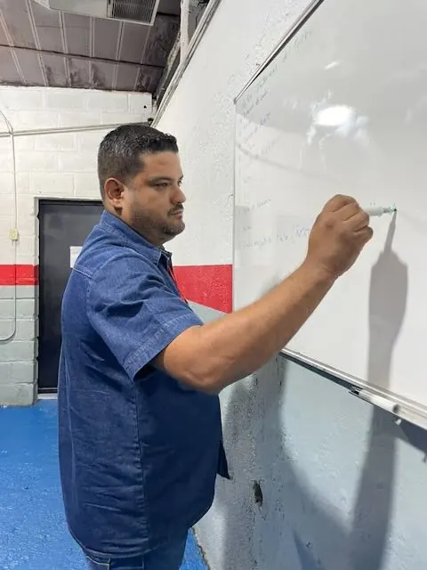 Instructor escribiendo en la pizarra durante la clase teórica