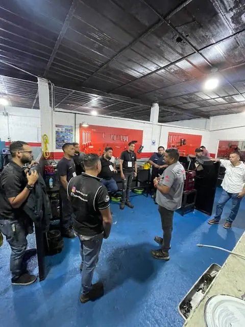 El instructor explicando al grupo reunido en el área de trabajo